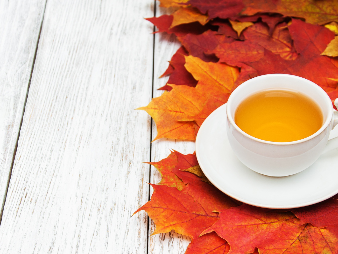 Чашка чая на столе с осенней листвой 