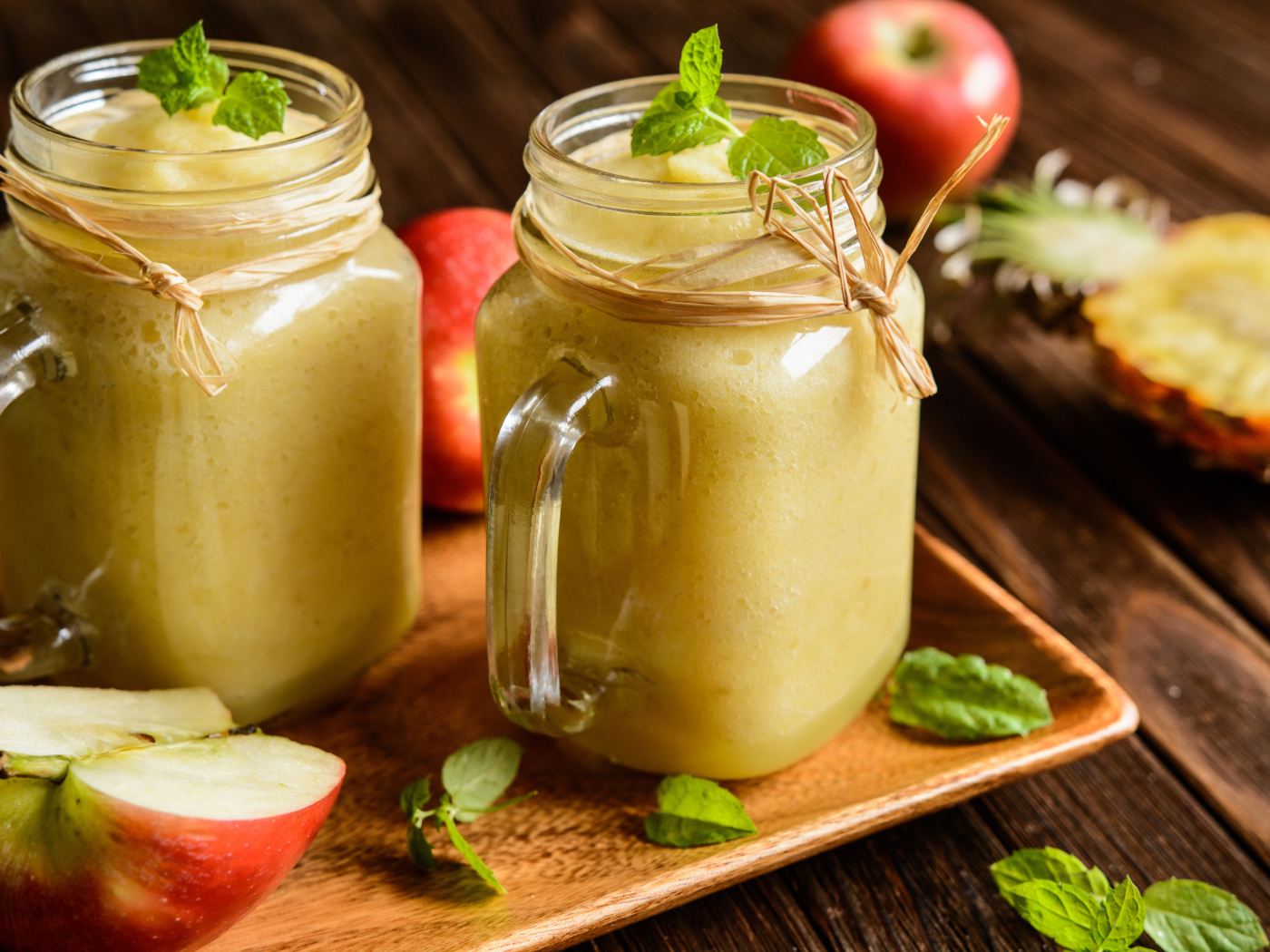 Смузи в стеклянных банках на столе с яблоками