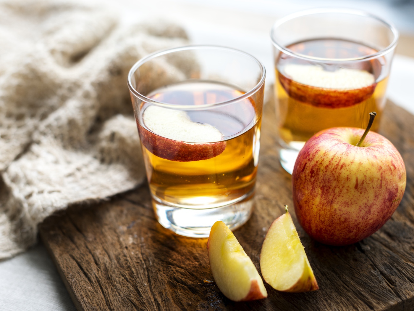 Два стакана сока на столе с яблоками 