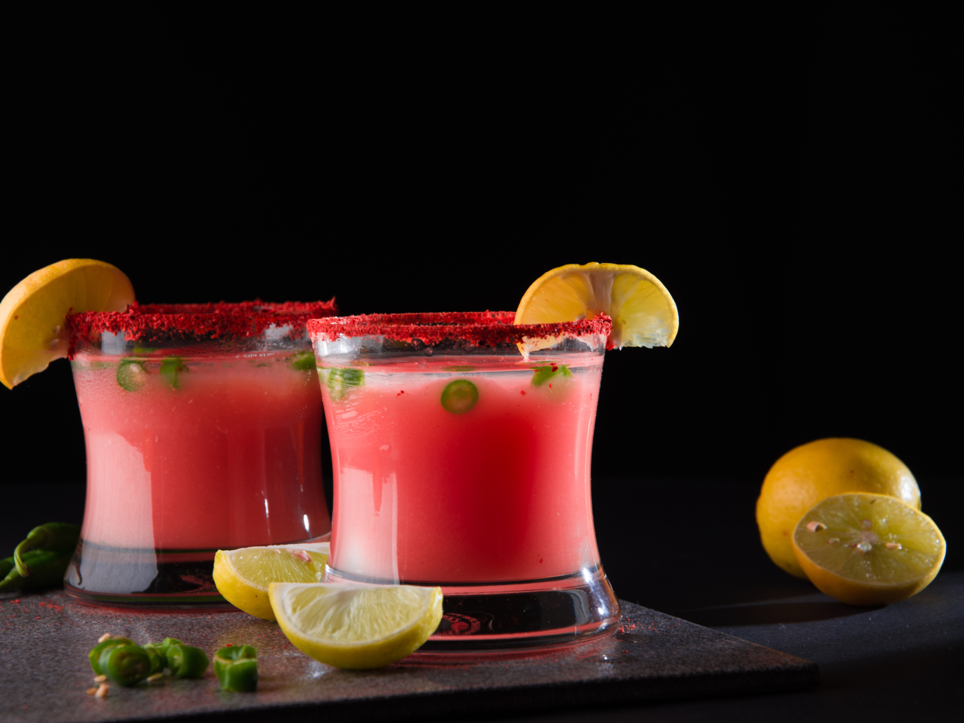 Два стакана с коктейлем на черном фоне с лимоном