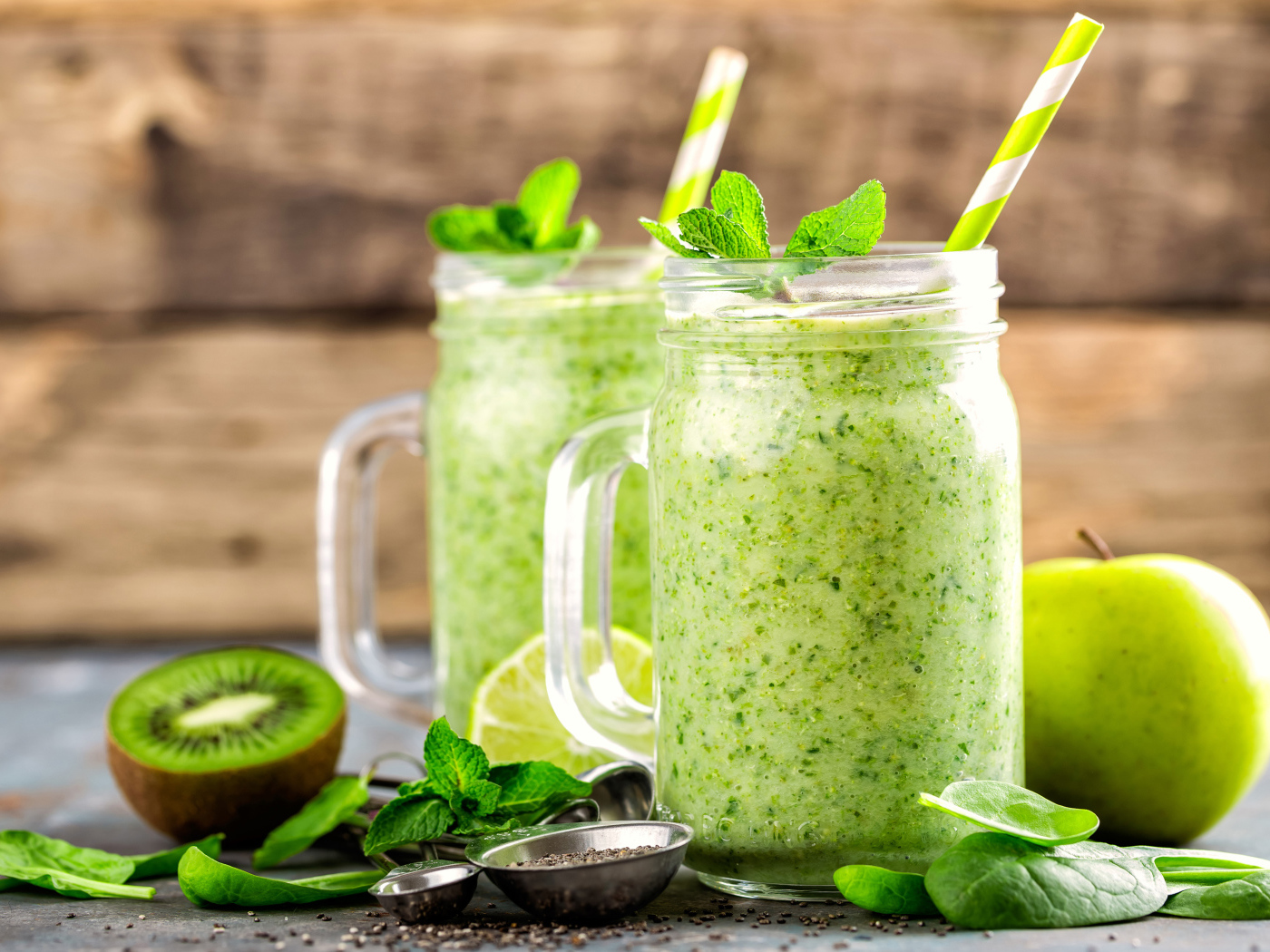 Два зеленых смузи на столе с киви, мятой и зеленым яблоком