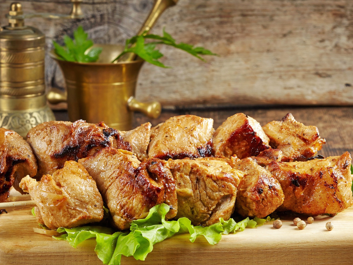 Аппетитный шашлык лежит на разделочной доске с листьями салата