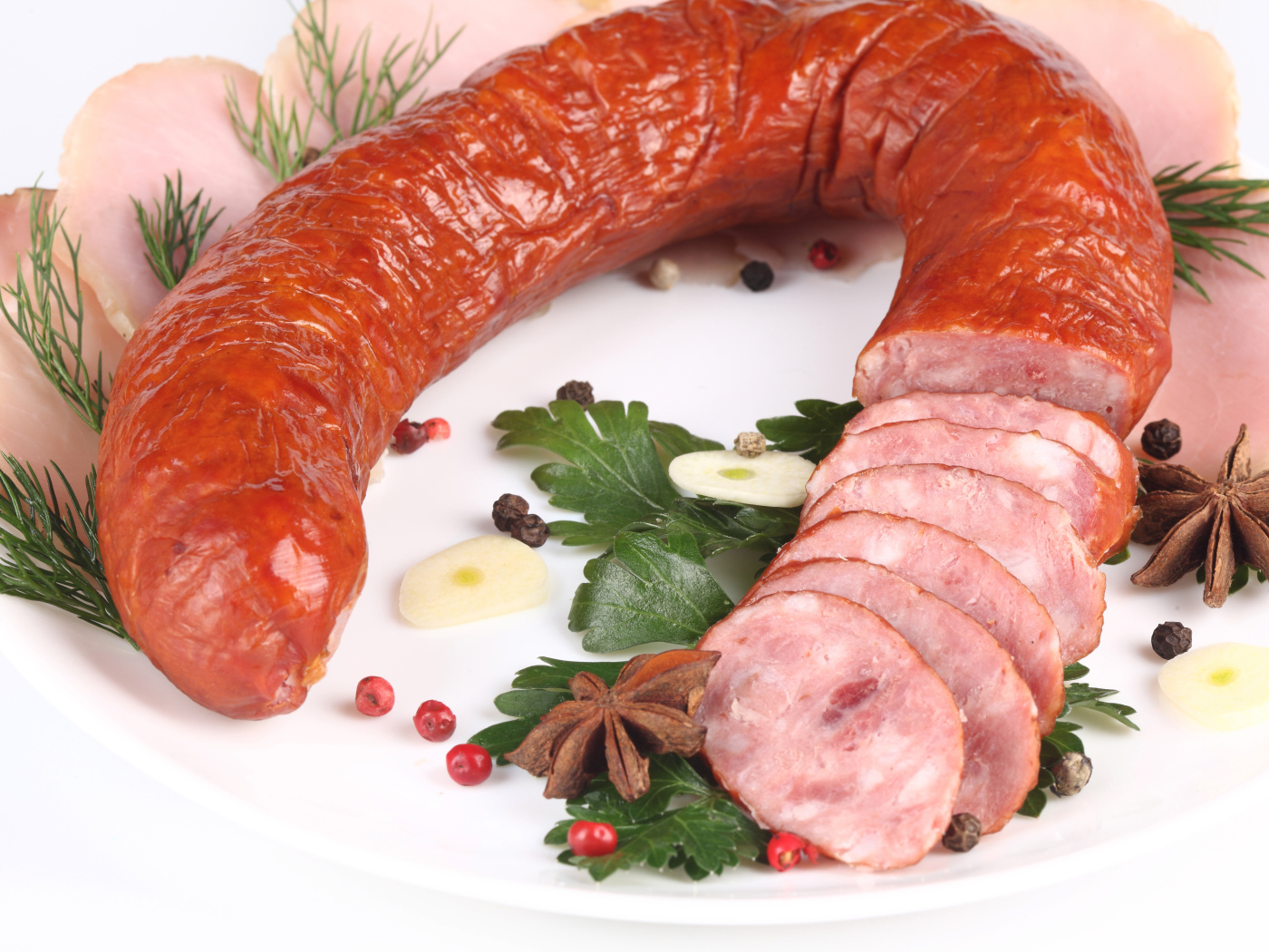 Аппетитная колбаса на белом фоне со специями и зеленью