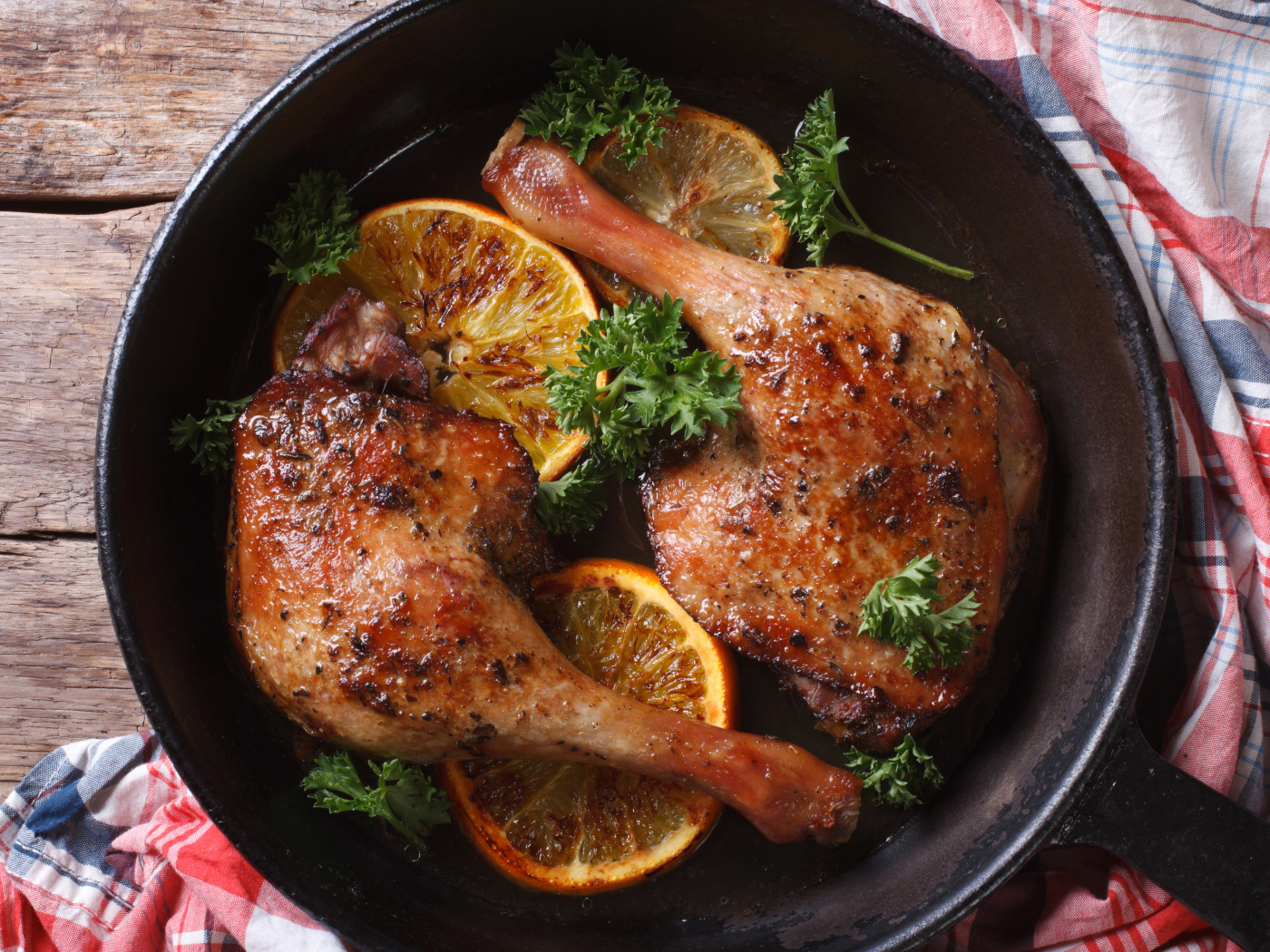 Куриные окорочка в сковороде с кольцами апельсина и петрушкой