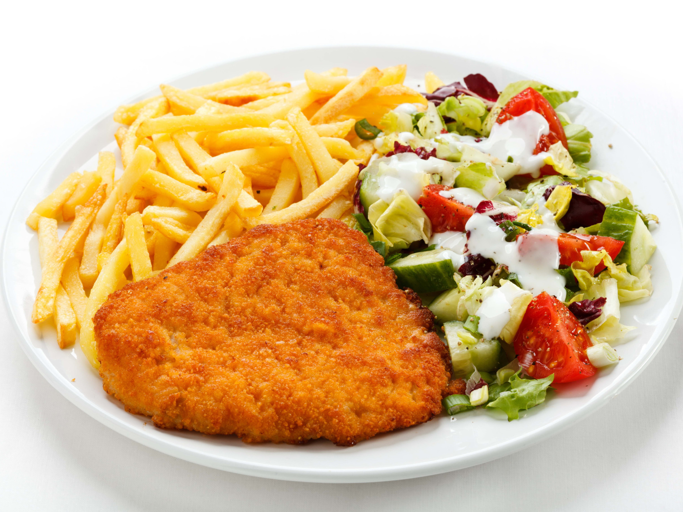 Отбивная с картофелем фри и салатом на большой белой тарелке