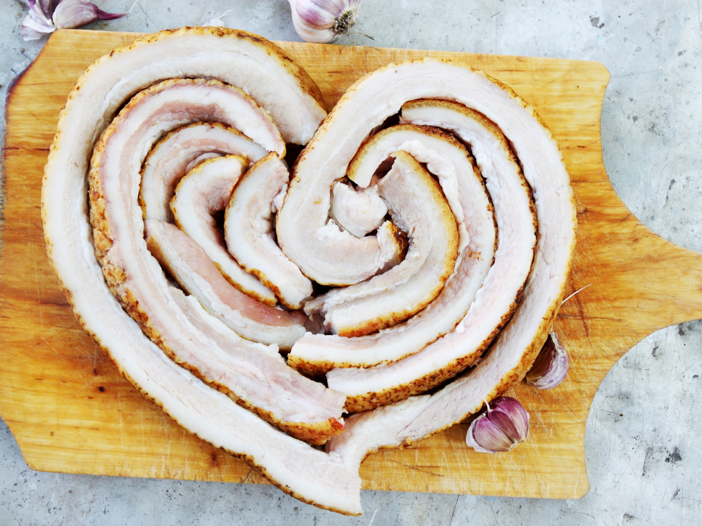 Сердце из свежего сала на доске с чесноком