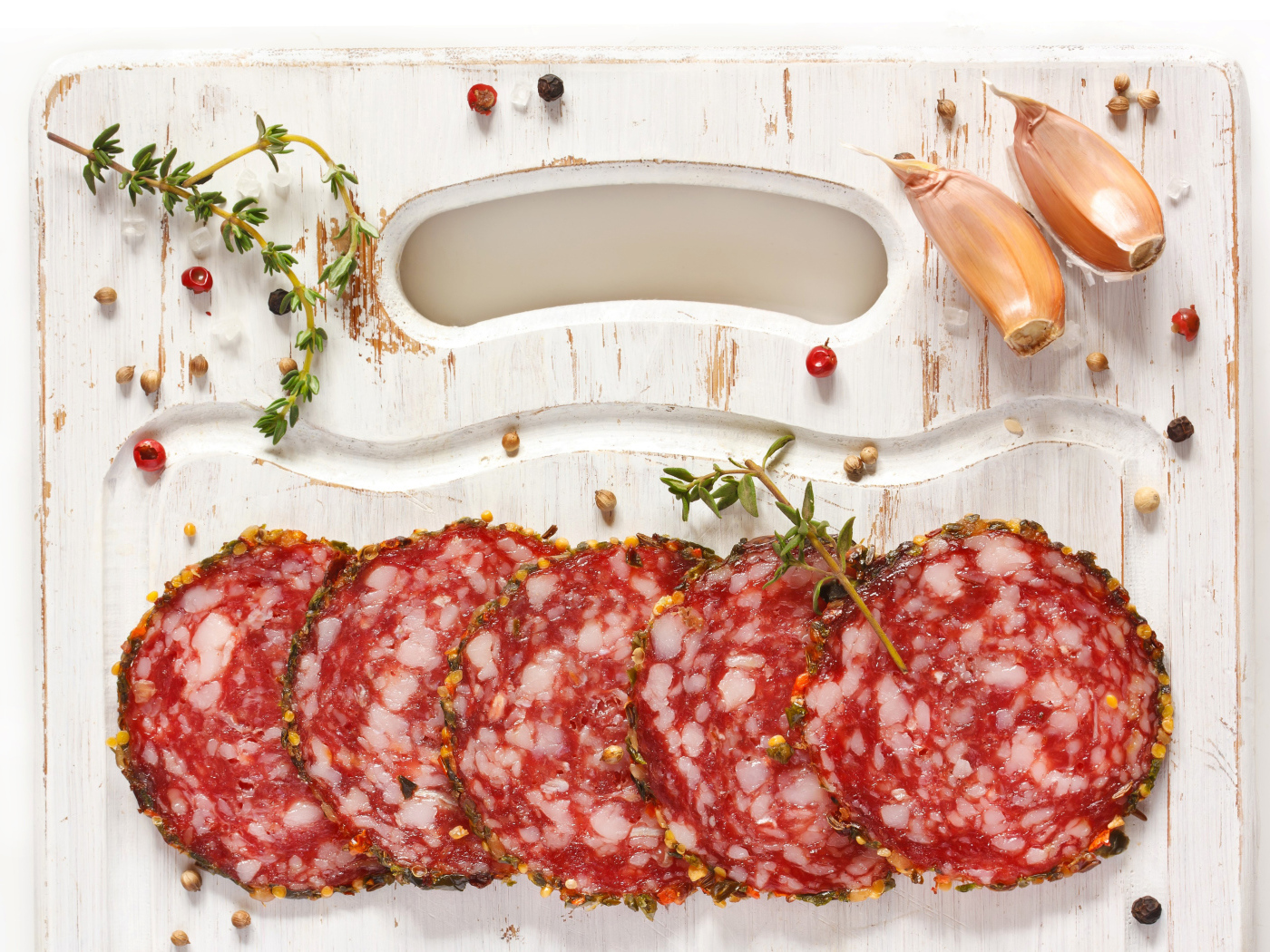 Нарезанная колбаса на разделочной доске со специями и чесноком