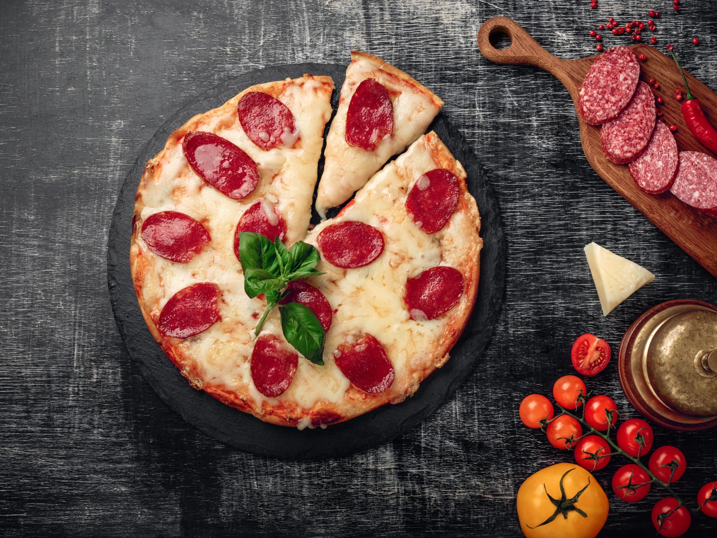 Пицца с сыром и салями на столе с помидорами и колбасой