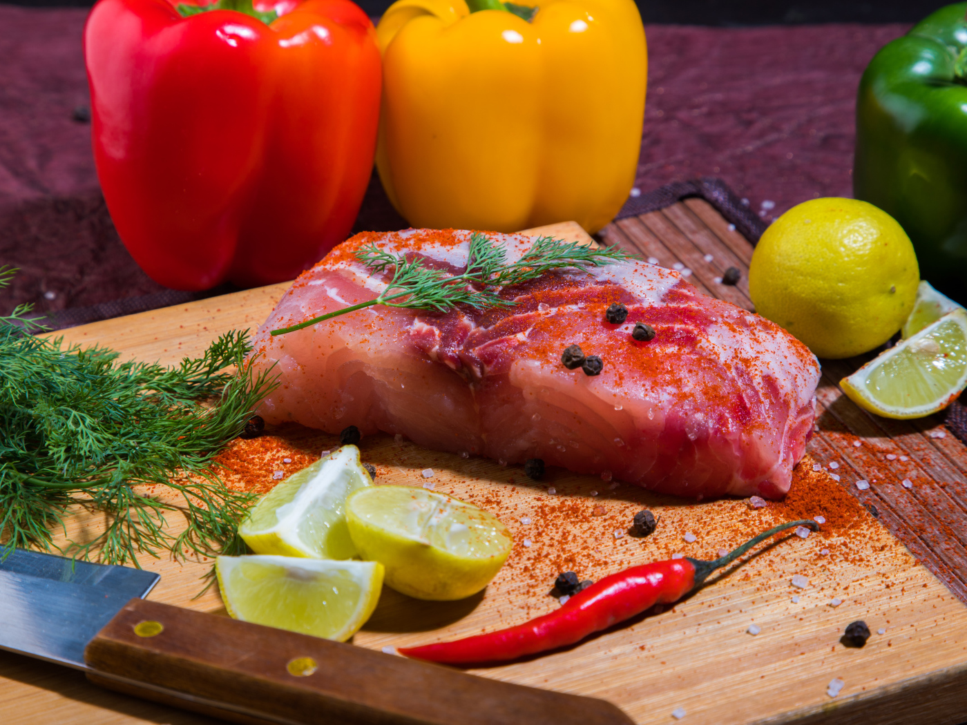 Кусок сырой рыбы на разделочной доске со специями, лимоном и болгарским перцем