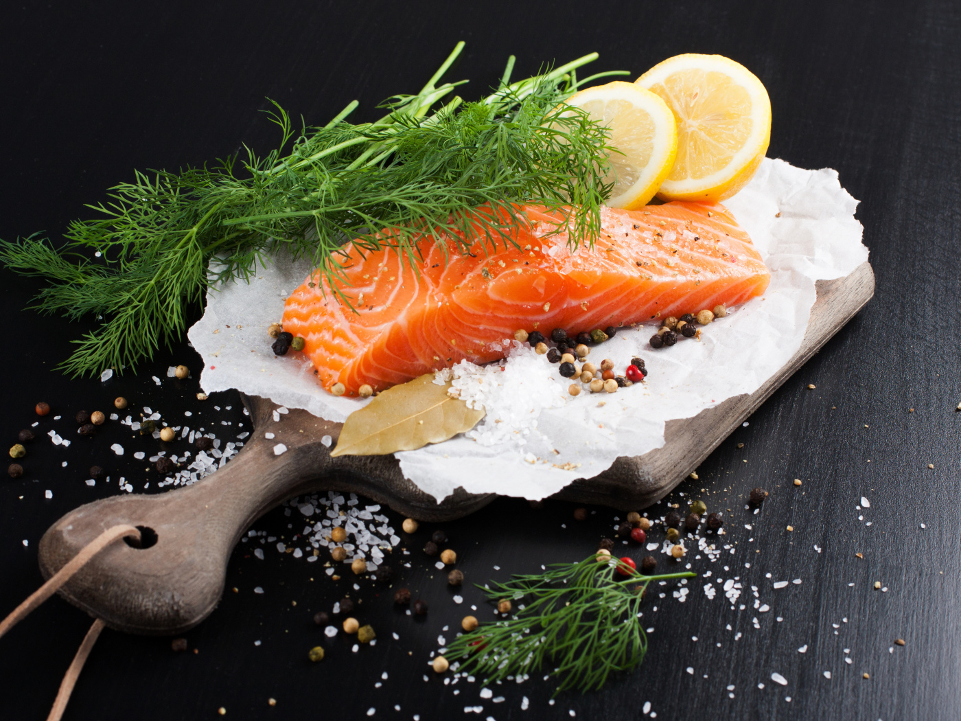 Кусок красной рыбы на доске с укропом и лимоном 