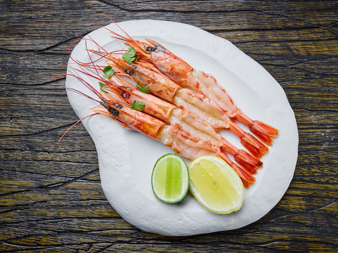 Аппетитные креветки на белой тарелке с лимоном