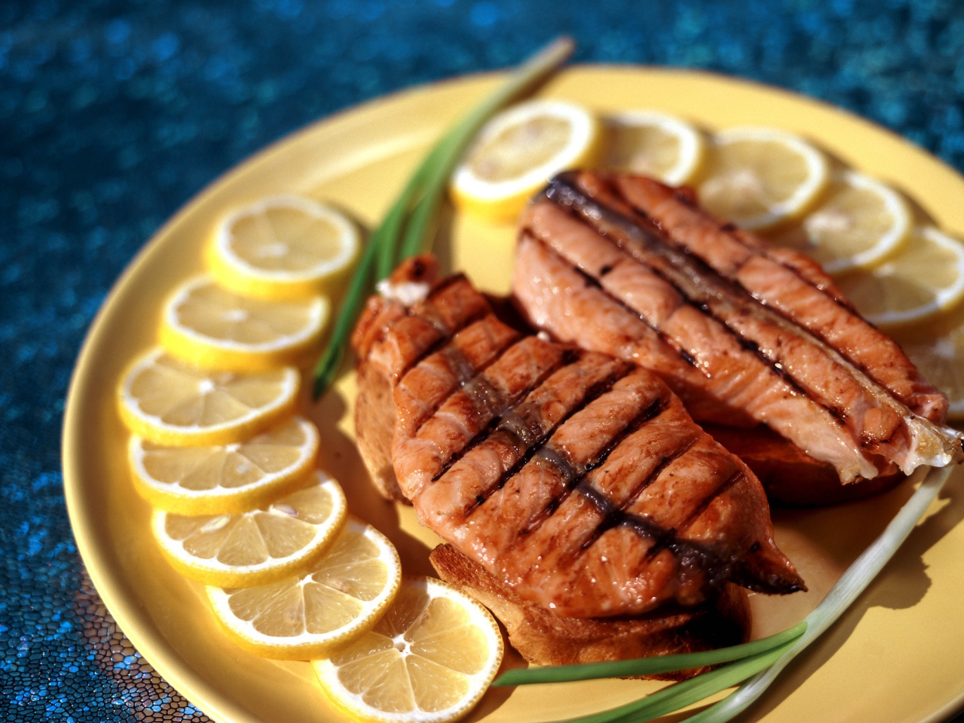 Зажаренная красная рыба с кусочками лимона и зеленым луком