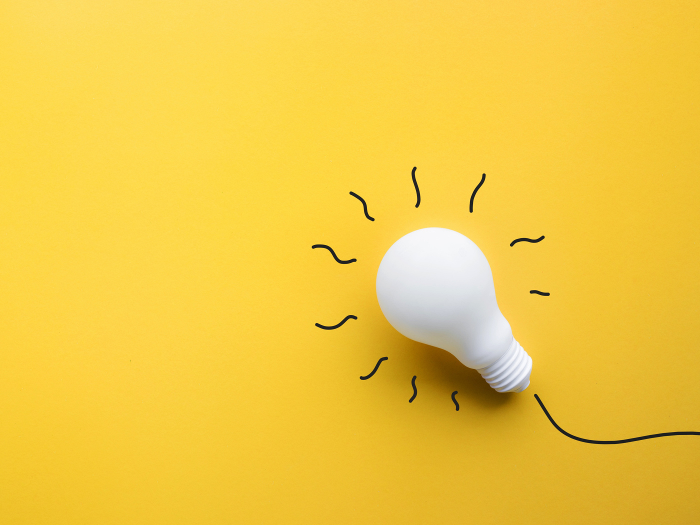 Белая лампочка лежит на желтой поверхности 