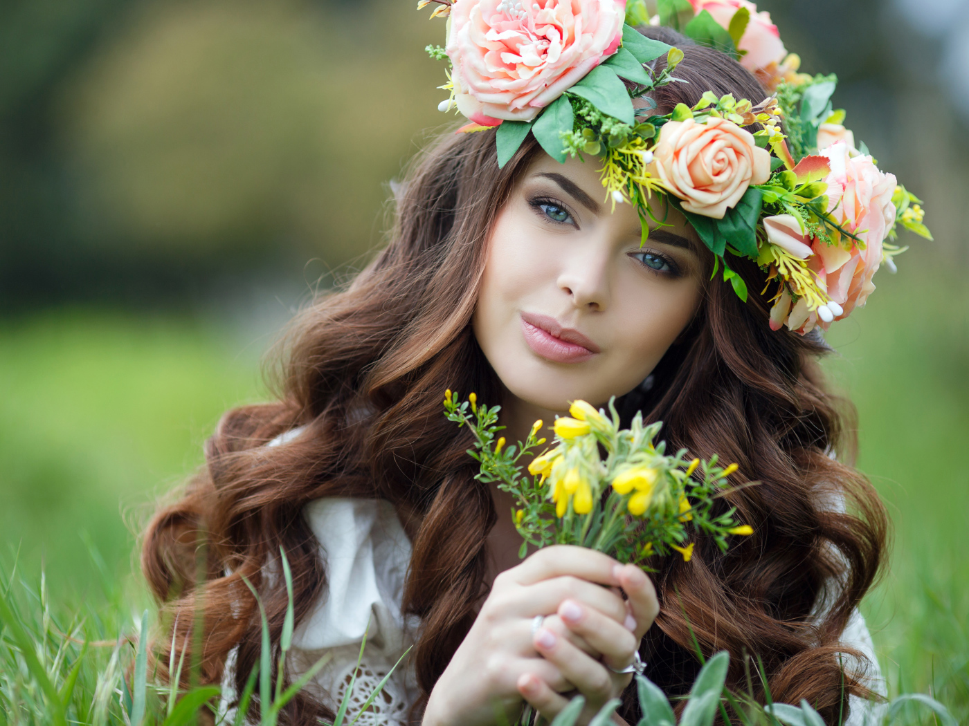 Красивая девушка с венком на голове лежит на траве