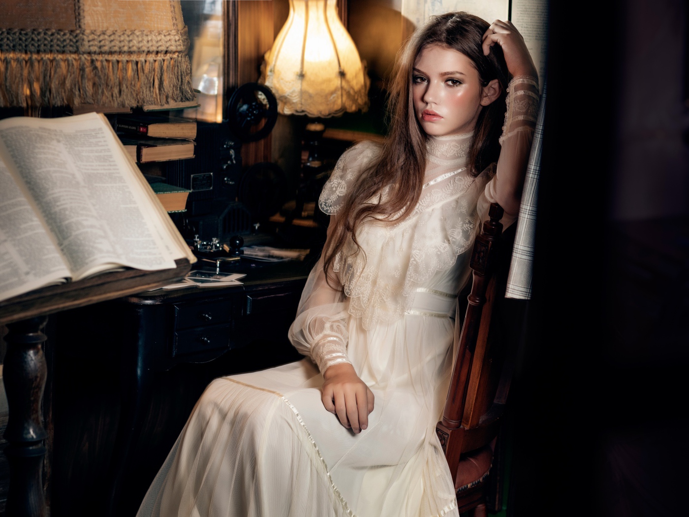 Девушка в красивом белом платье сидит на стуле у стола