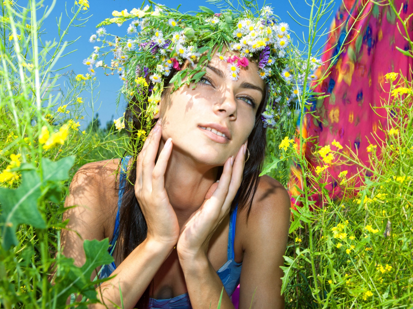 Молодая девушка с венком из полевых цветов лежит в траве