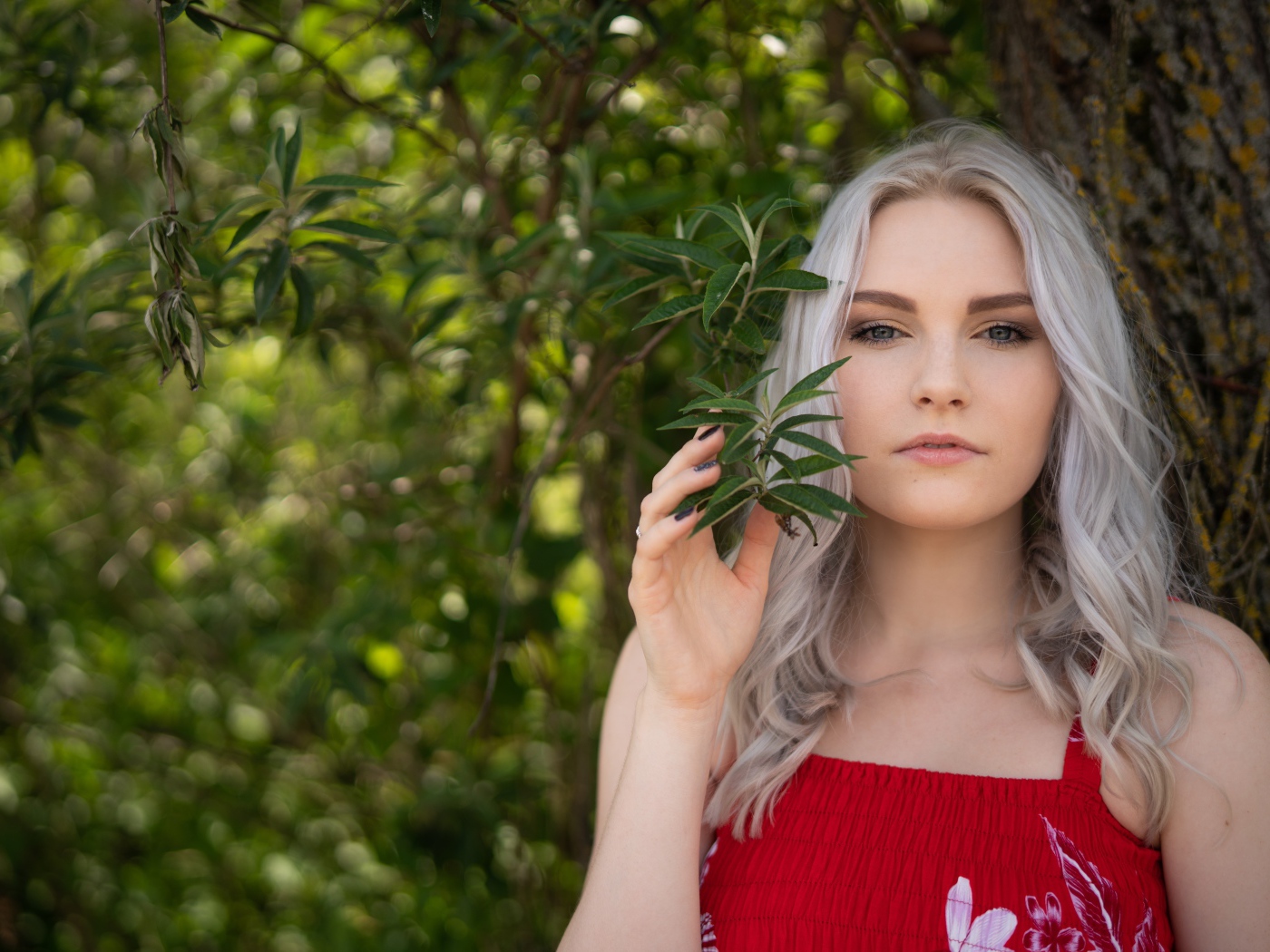 Красивая блондинка стоит у дерева 