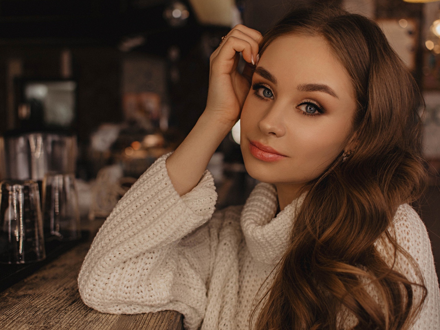 Красивая голубоглазая девушка в белом свитере в кафе