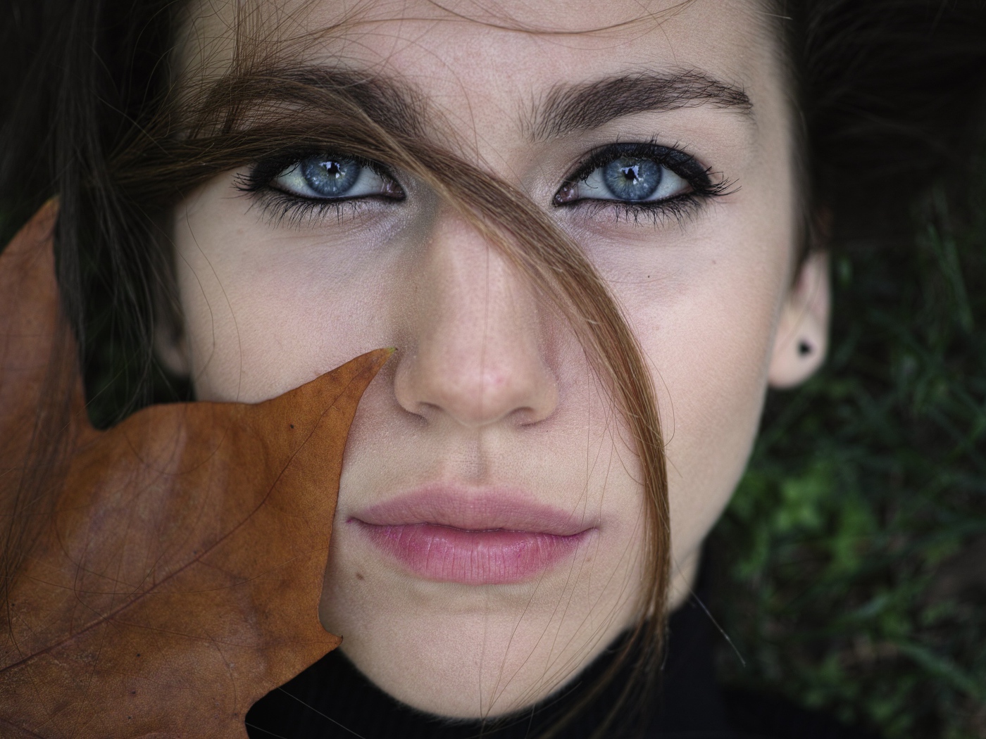 Красивая голубоглазая девушка с желтым листом у лица