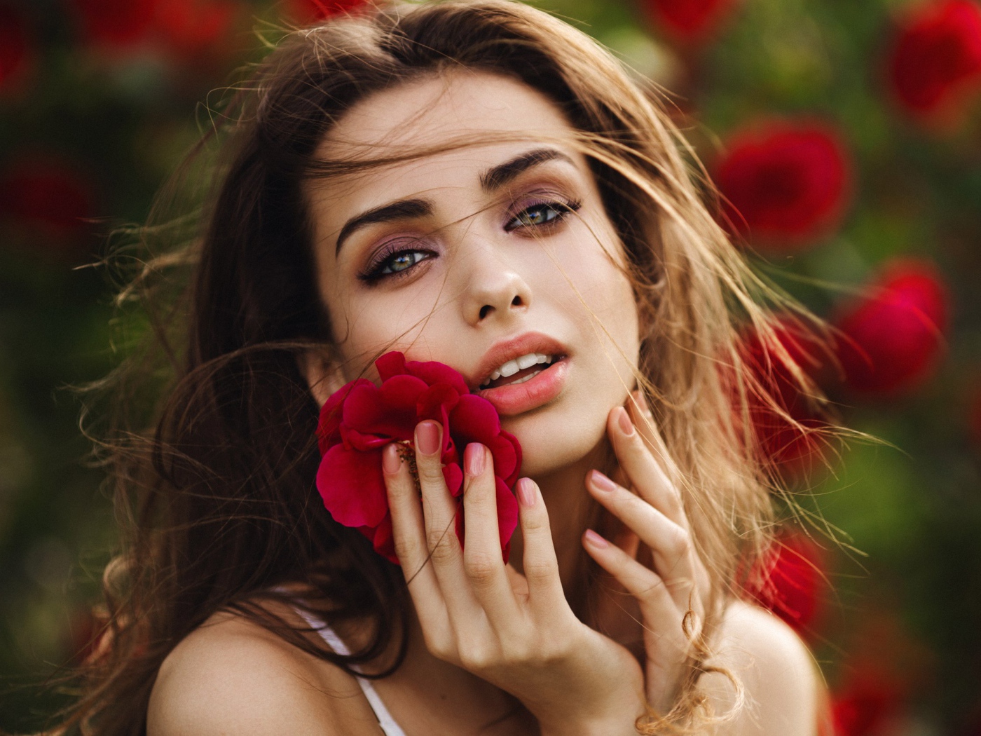 Красивая девушка шатенка с цветком у лица