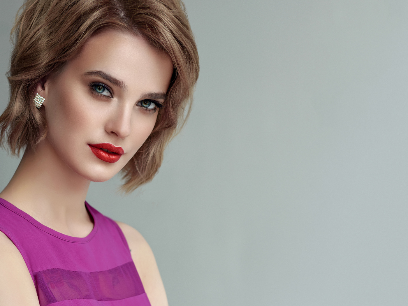 Красивая девушка шатенка с короткой стрижкой на сером фоне