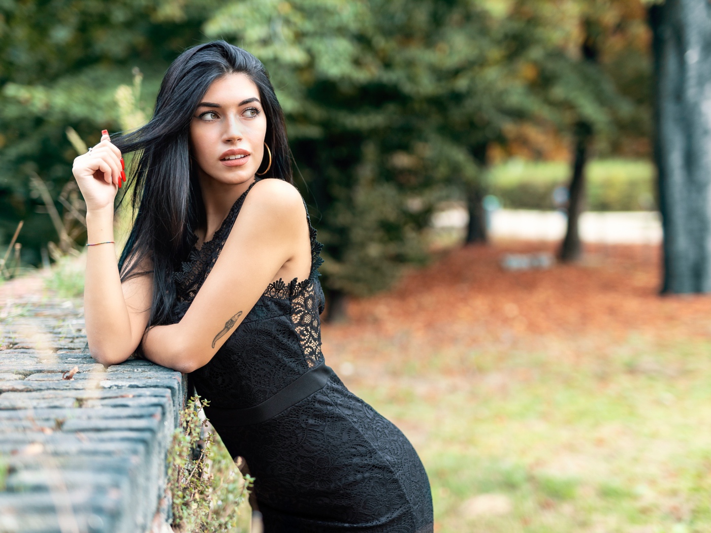 Красивая брюнетка в черном платье в парке