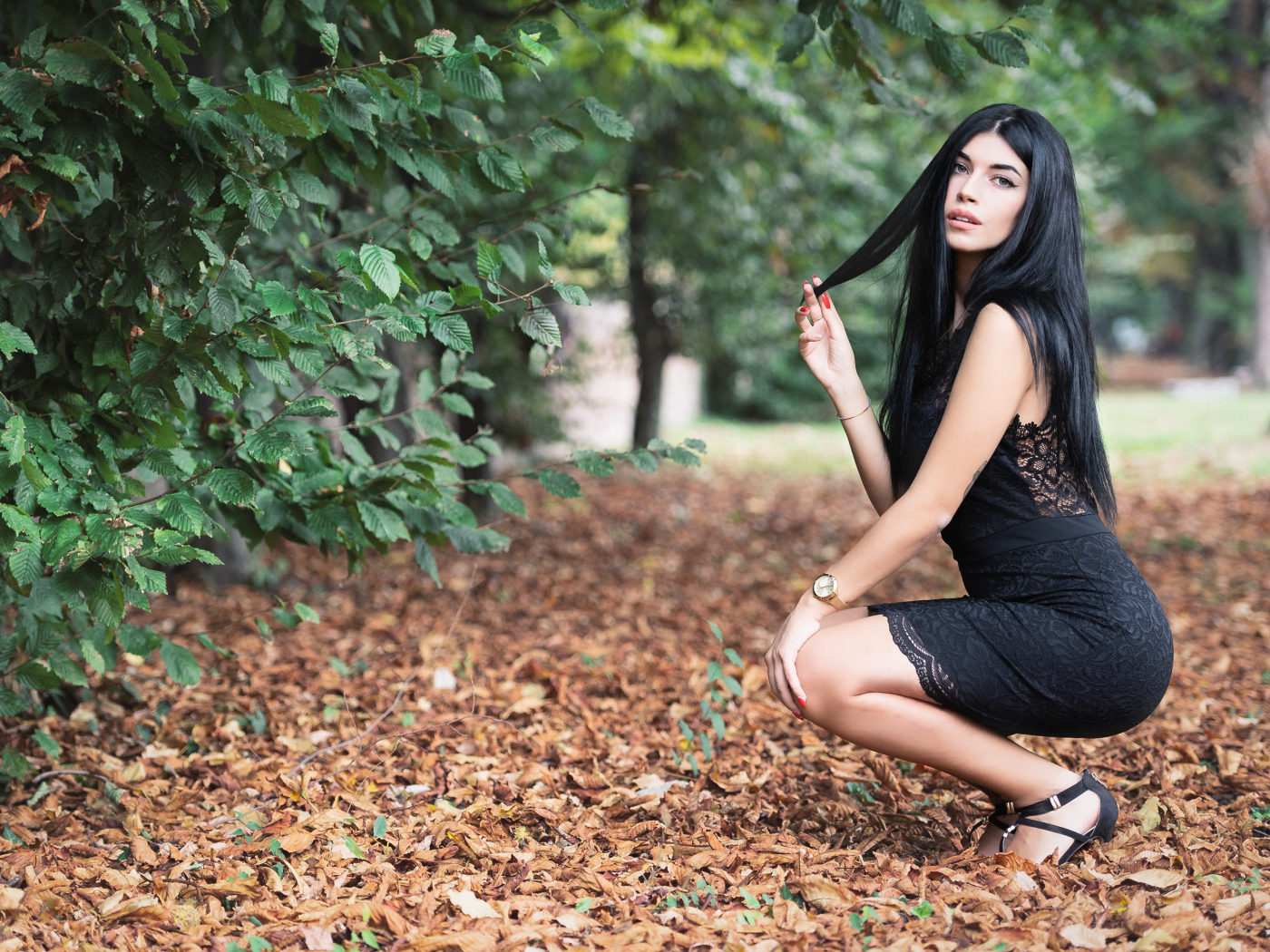 Красивая брюнетка в черном платье в парке осенью 