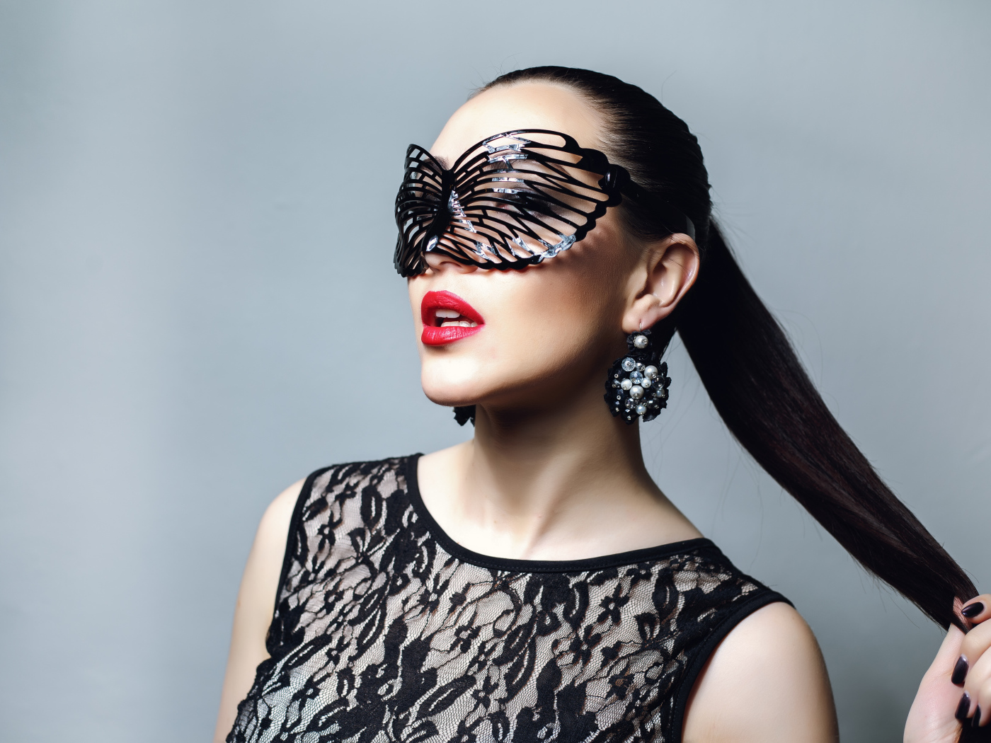 Красивая модная девушка в черной маске на сером фоне