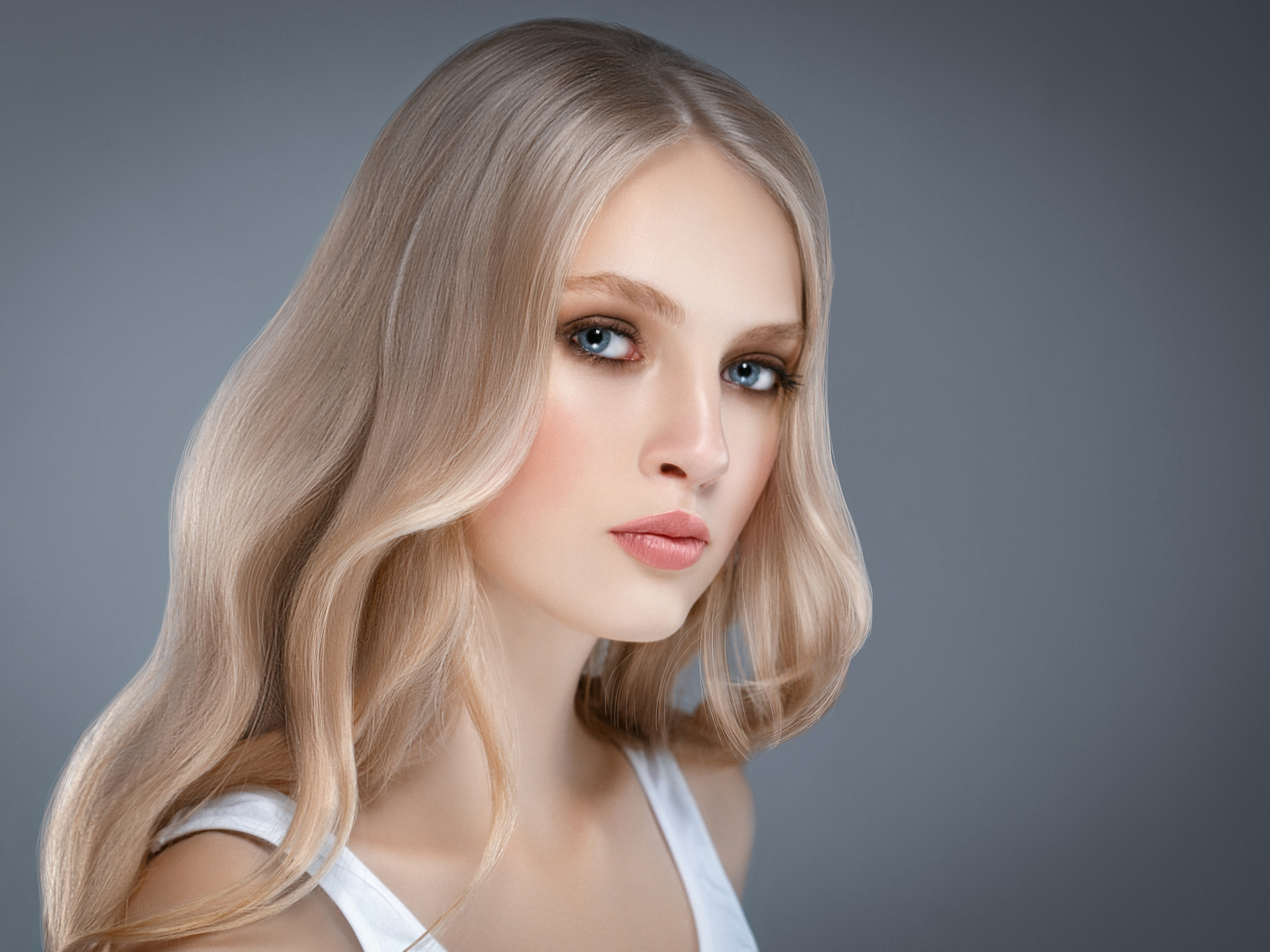 Красивая нежная голубоглазая блондинка на сером фоне