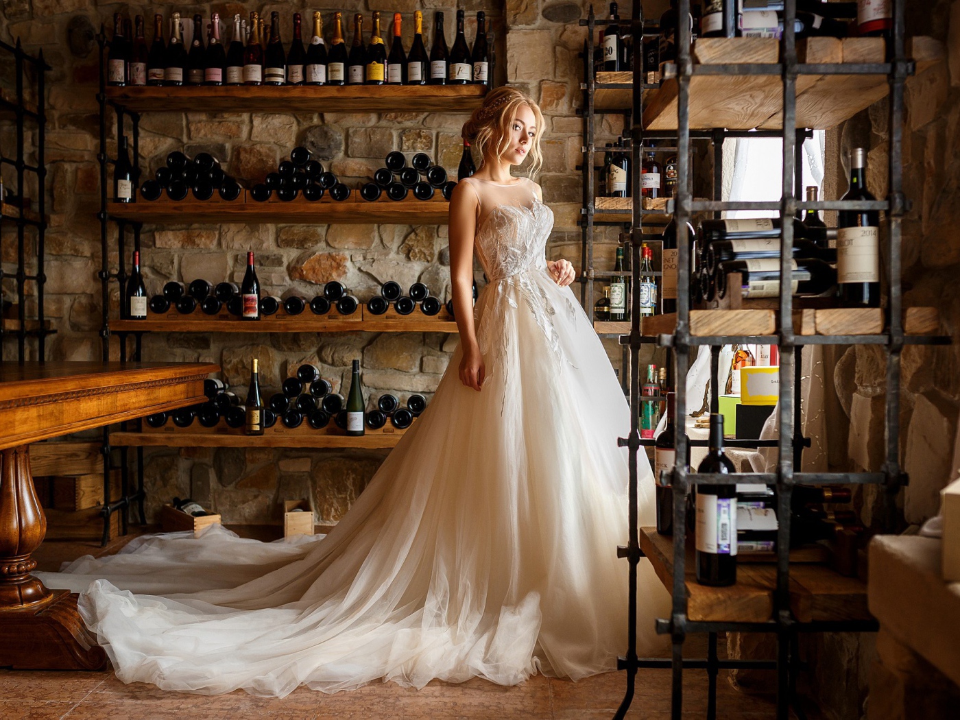 Красивая девушка в пышном свадебном платье в винном погребе