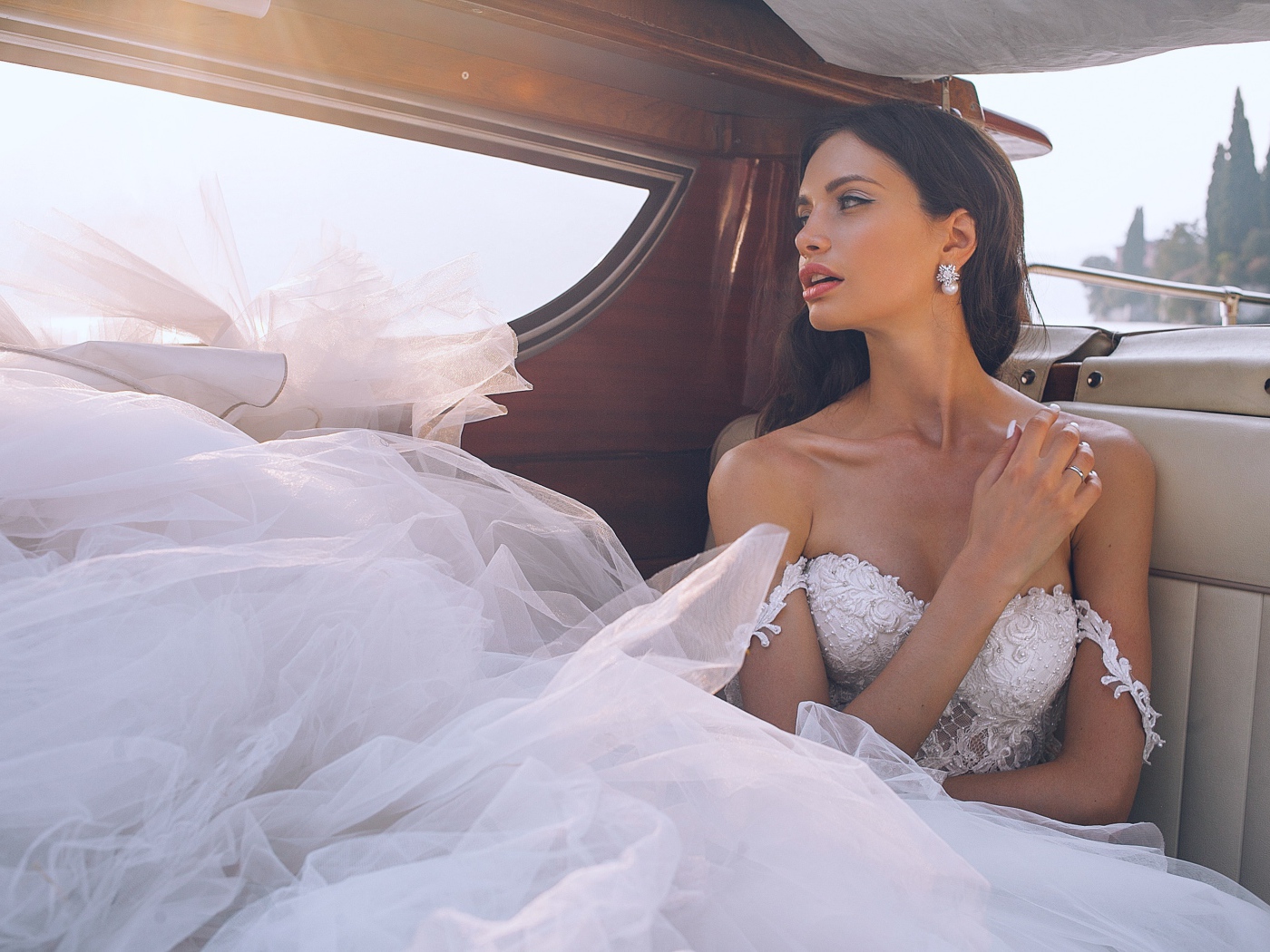 Красивая девушка в белом свадебном платье в машине
