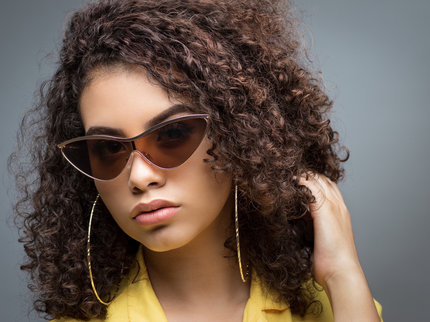 Красивая девушка в солнечных очках на сером фоне