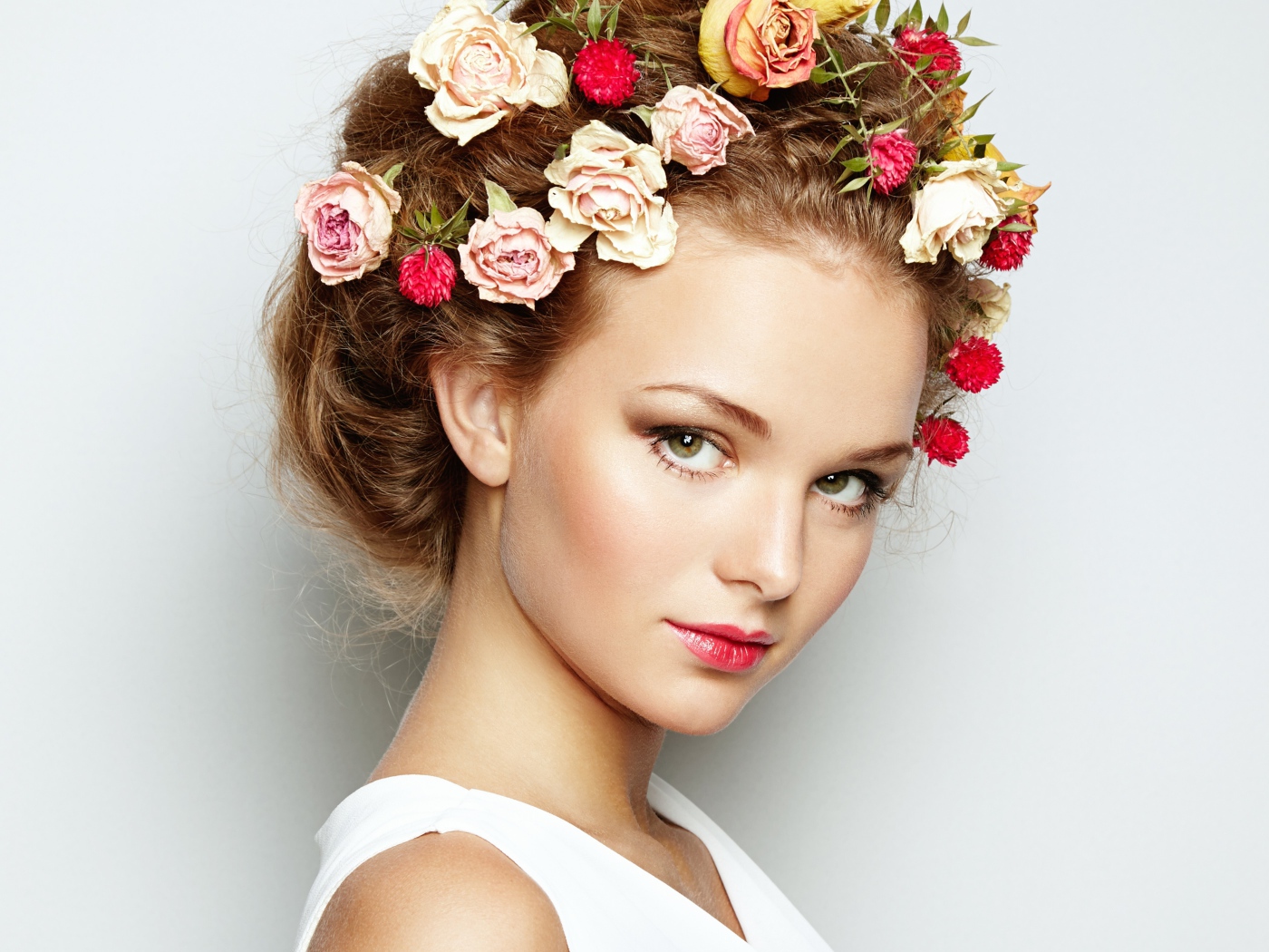 Красивая девушка с цветами в волосах на сером фоне