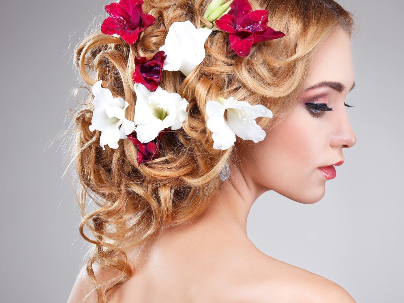 Красивая девушка с цветами петунии в волосах на сером фоне
