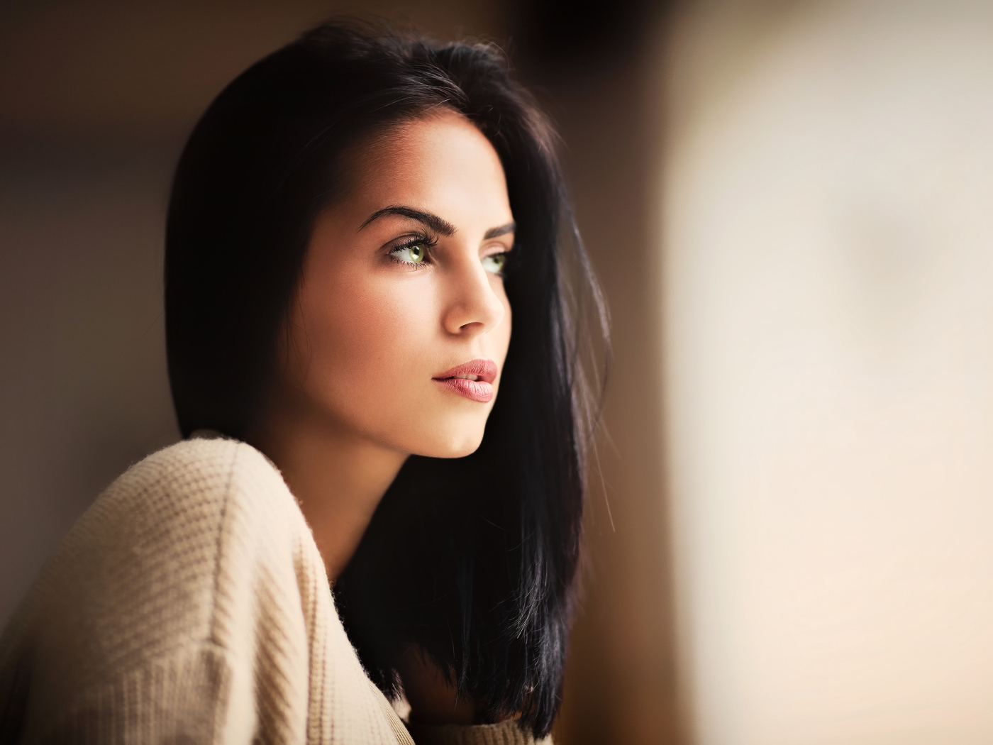 Красивая девушка зеленоглазая смотрит в окно 