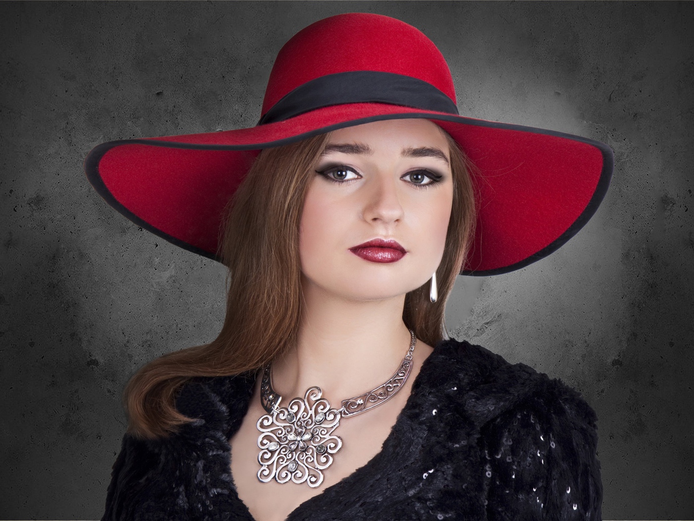 Красивая стильная девушка в красной шляпе с украшением на шее 