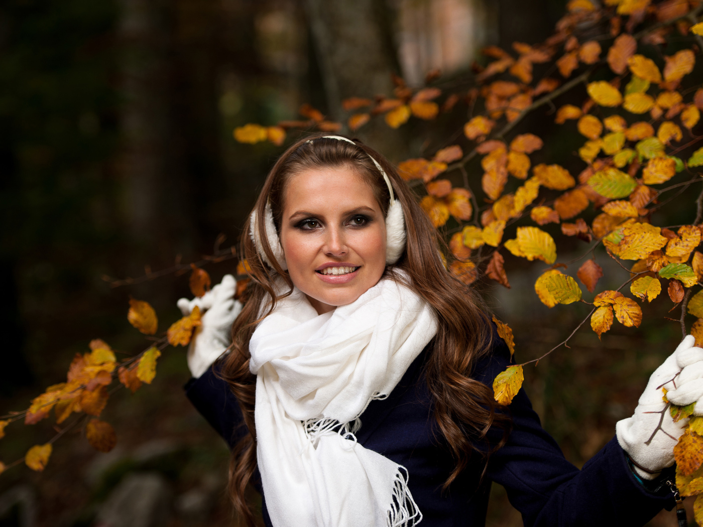 Девушка шатенка с белым шарфом стоит у дерева с желтыми листьями