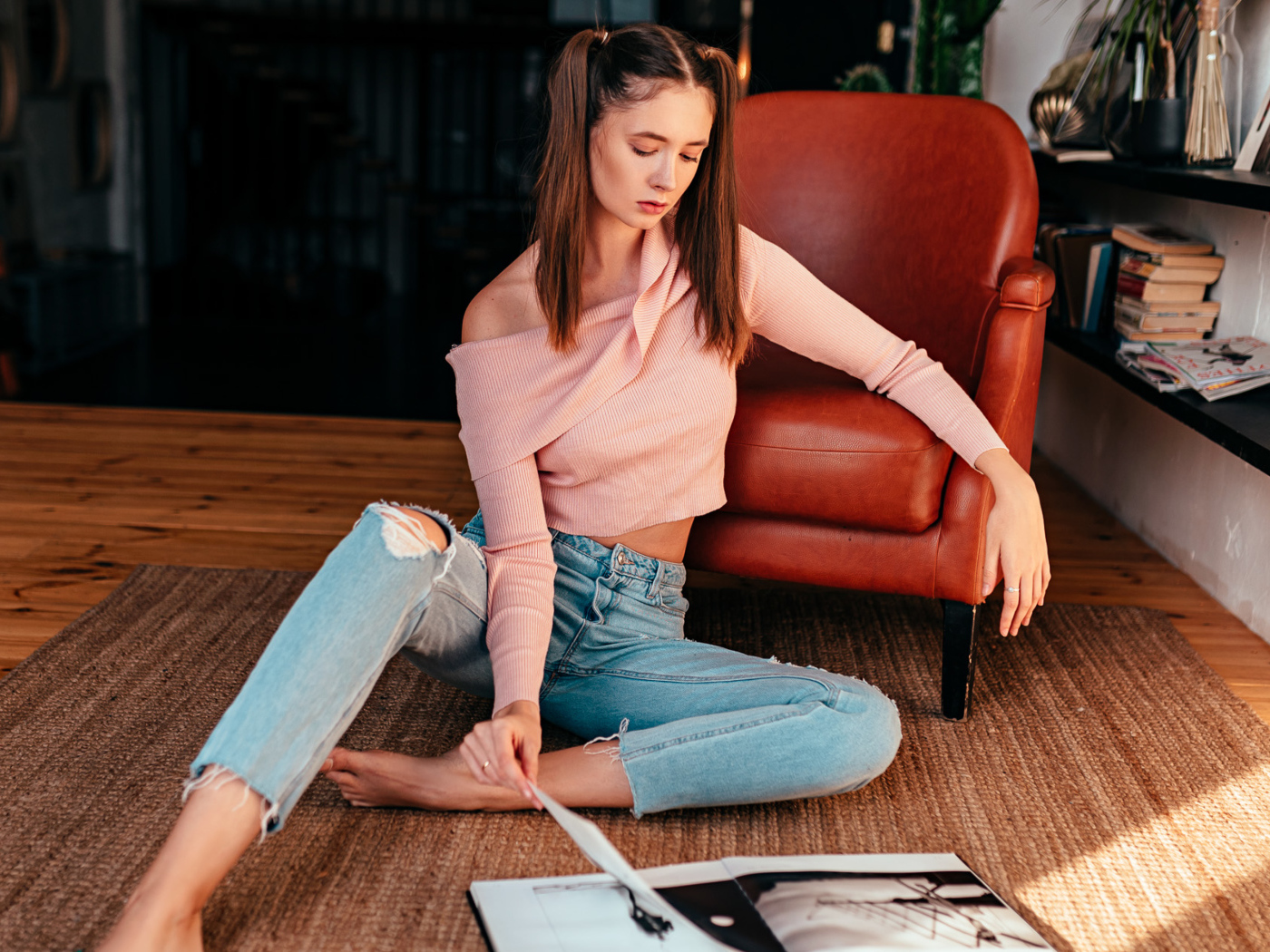 Девушка читает журнал на полу у кожаного кресла