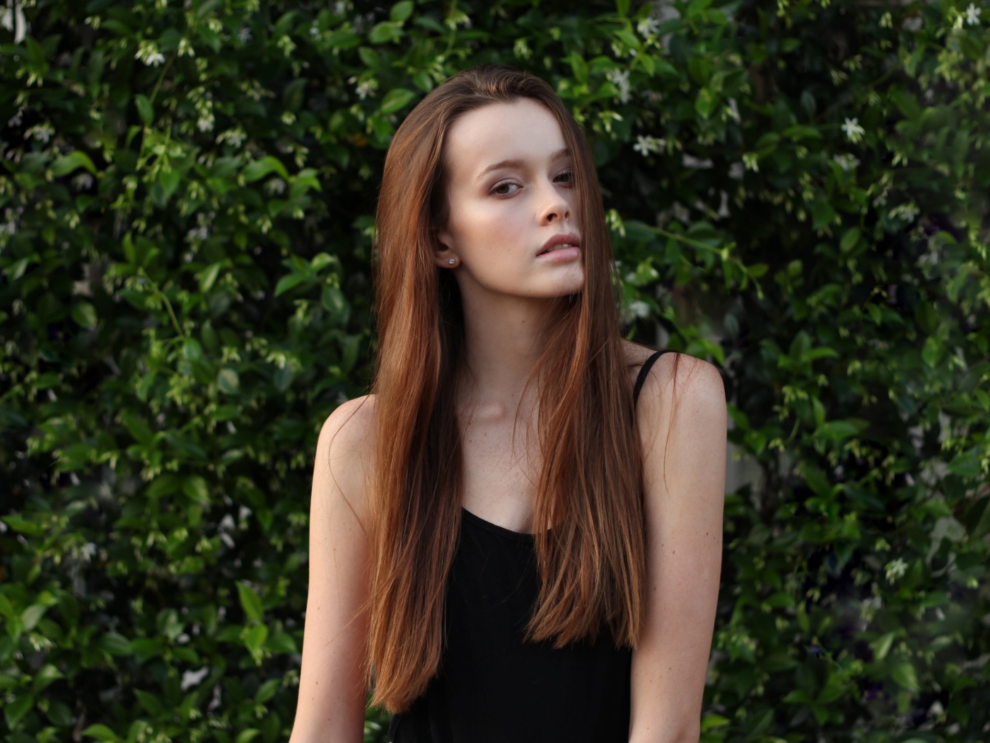 Длинноволосая шатенка на фоне зеленых зарослей