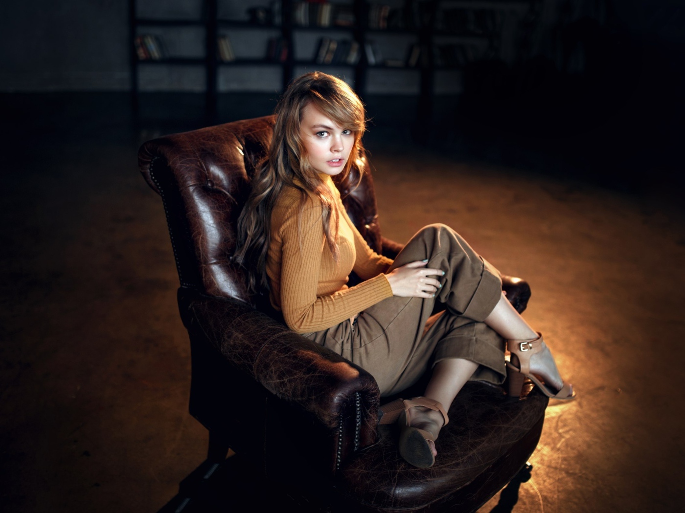 Нежная девушка модель сидит в кожаном кресле
