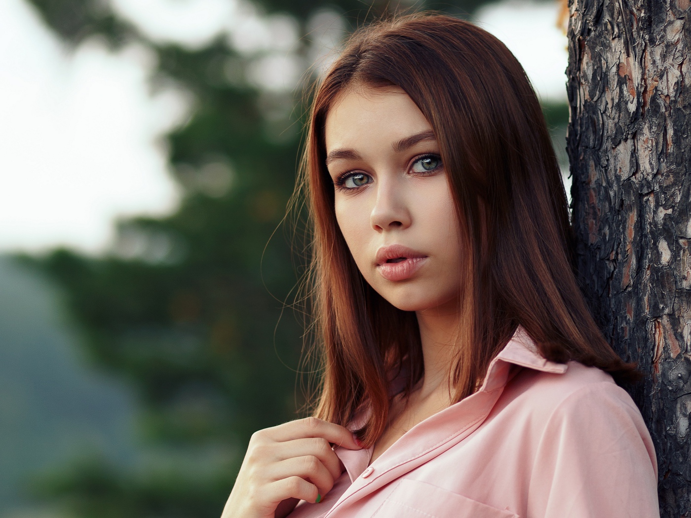 Нежная девушка стоит у дерева