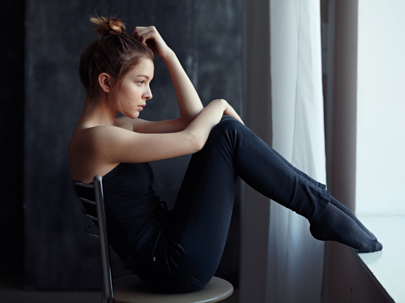 Девушка в черном наряде сидит на стуле