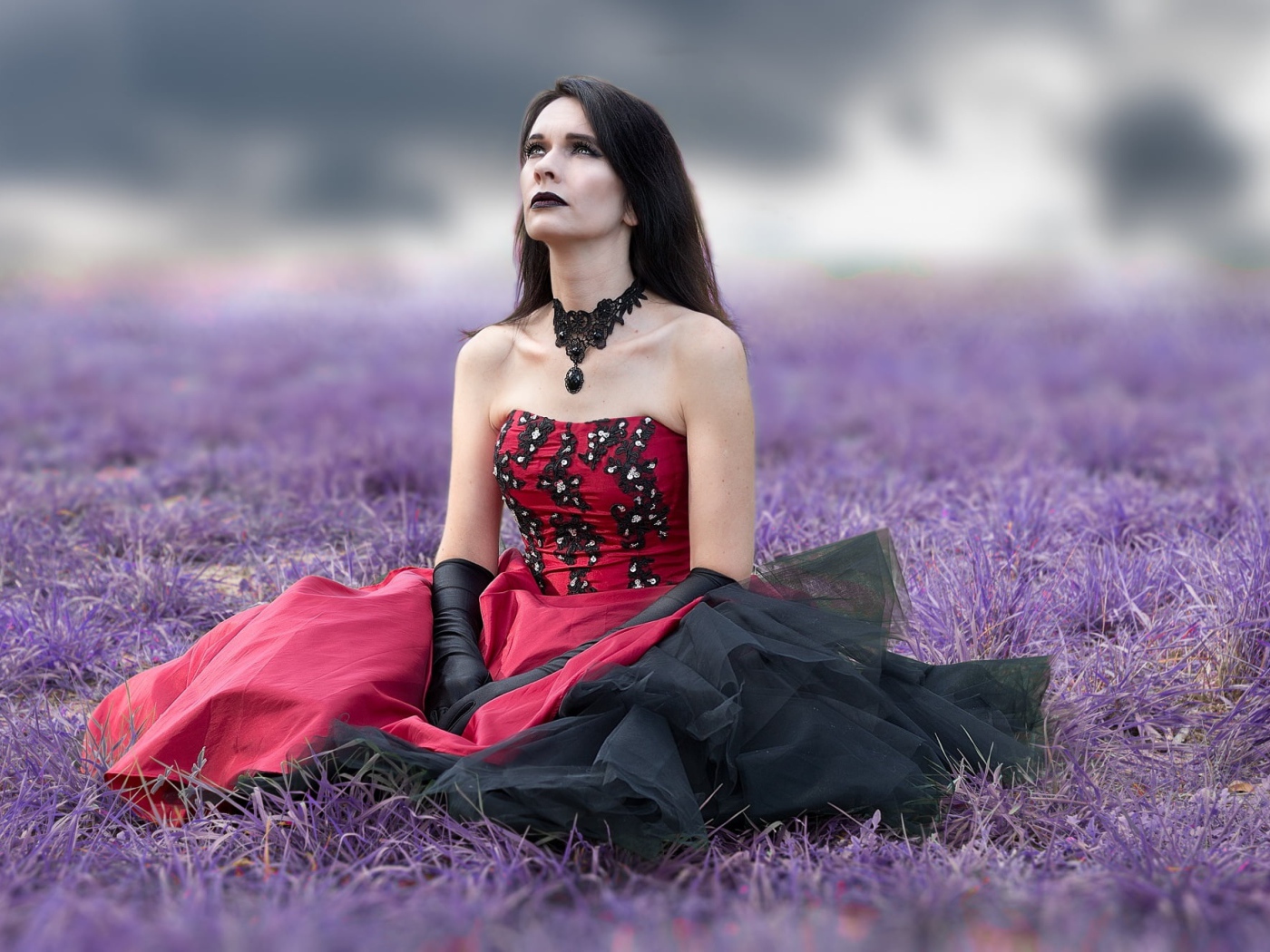 Девушка с макияжем в красивом платье сидит на траве