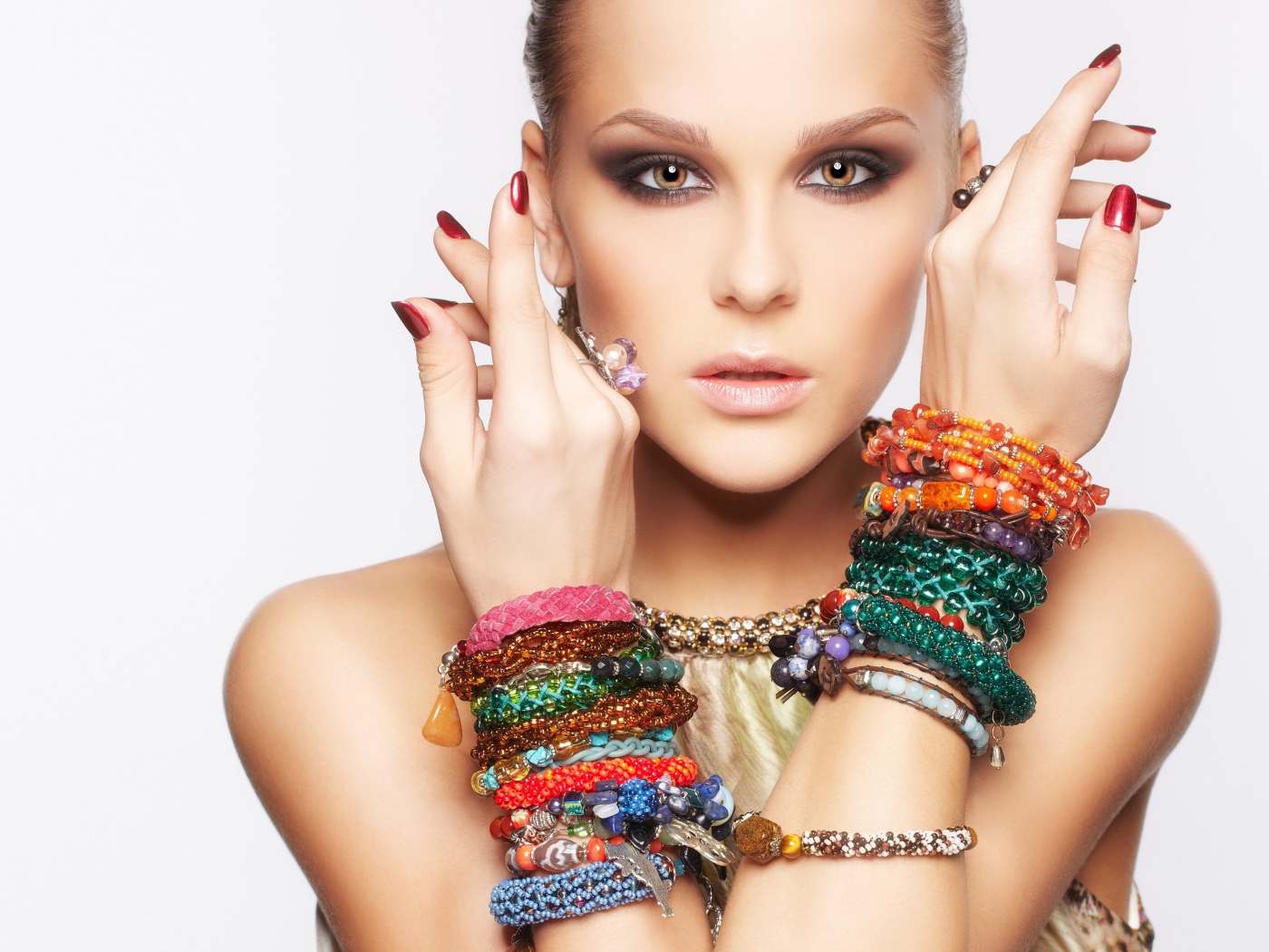 Молодая кареглазая девушка с браслетами на руках на белом фоне