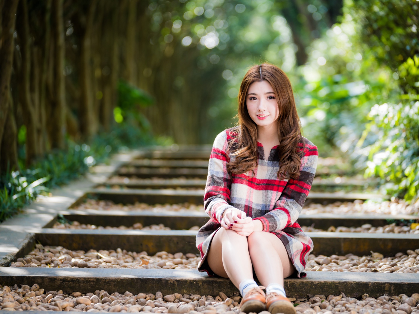 Молодая улыбающаяся азиатка сидит на дороге