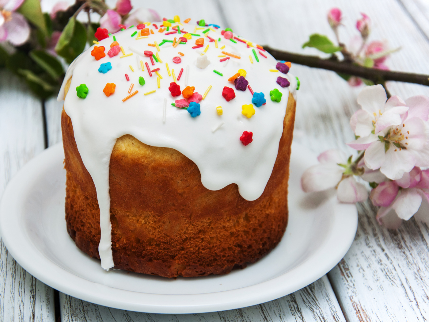 Красивый кулич с белой глазурью на столе с веткой яблони на Великий праздник Пасха