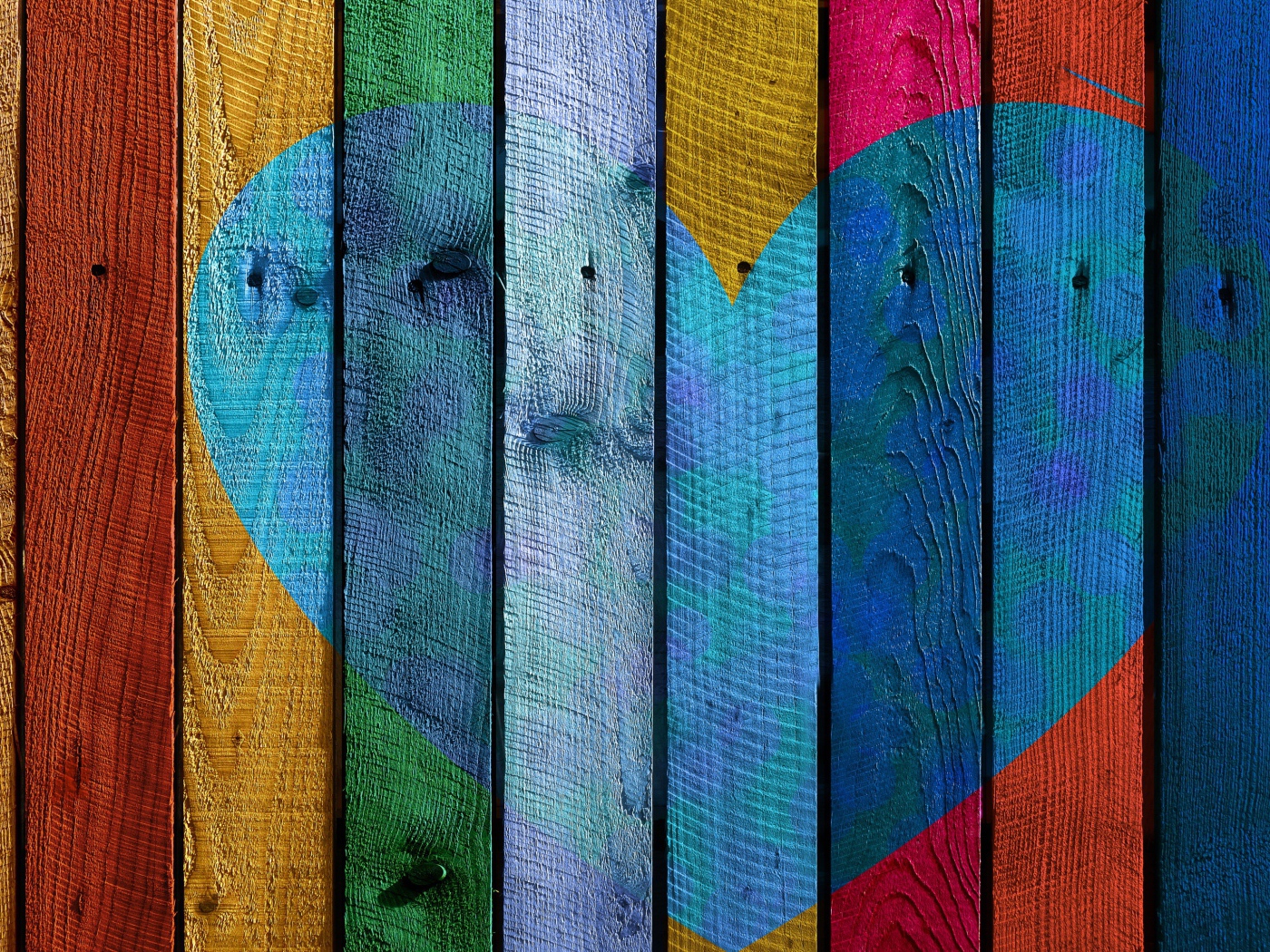 Голубое сердце нарисовано на разноцветном заборе