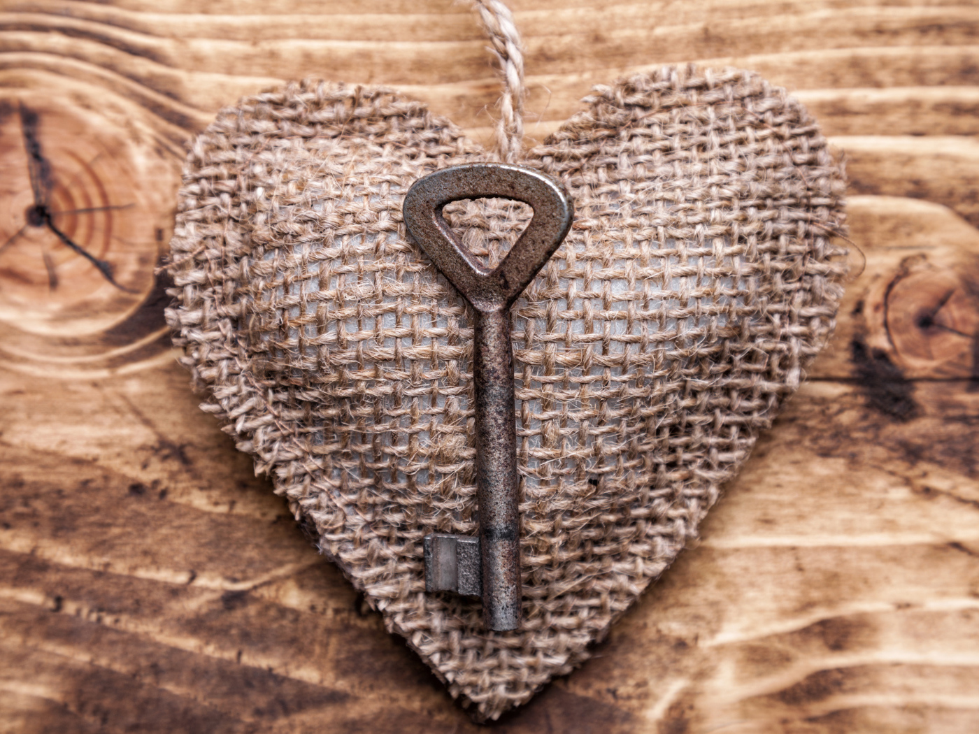 Сердечко из мешковины с ключом на деревянном фоне
