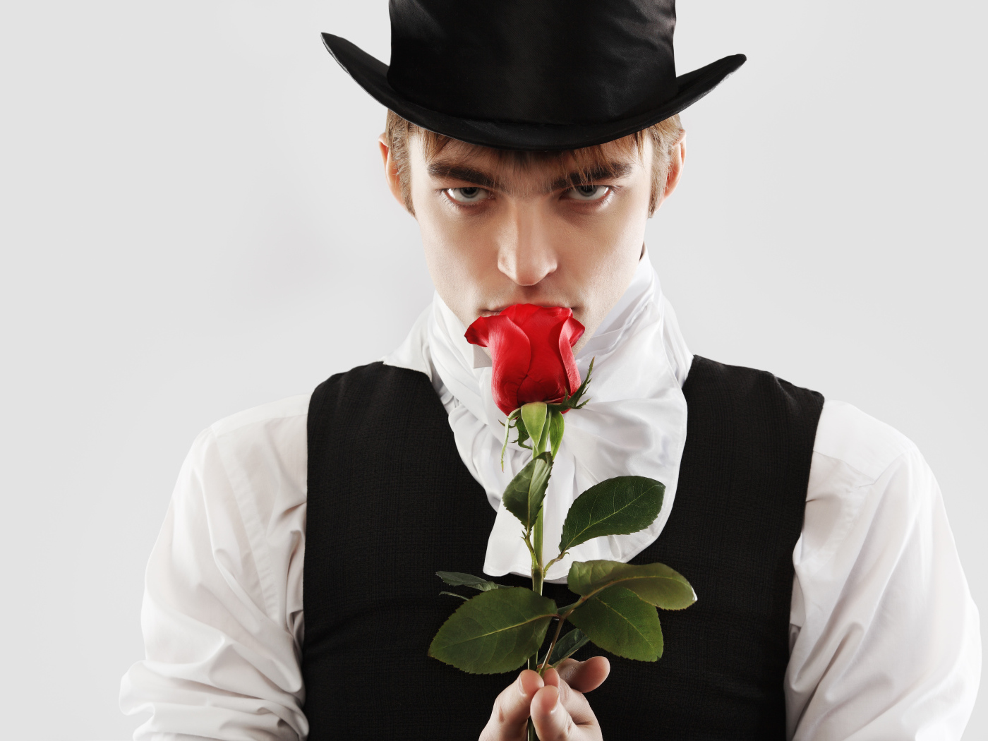 Guy in a top hat with a red rose in his hand on a gray background