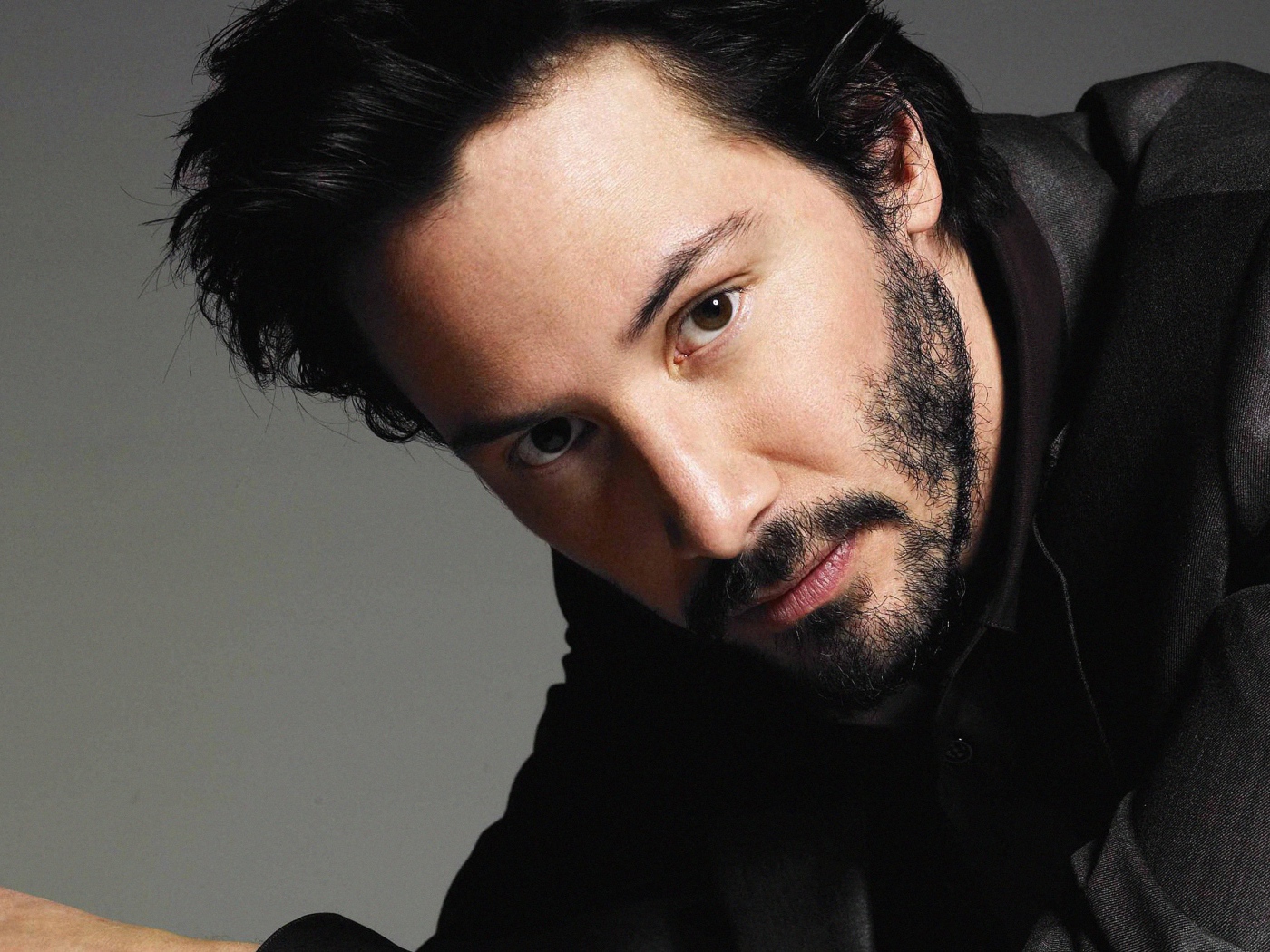 Актер Киану Ривз в костюме на сером фоне